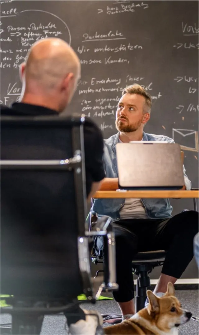Besprechung an der Kreidetafel im Particulate-Büro, Bürohund inklusive